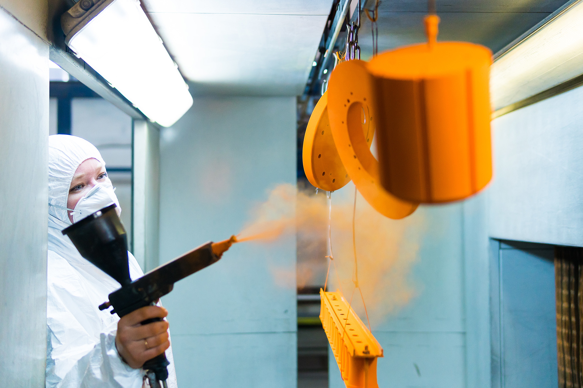 Application d'un revêtement thermolaqué orange sur des pièces métalliques suspendues