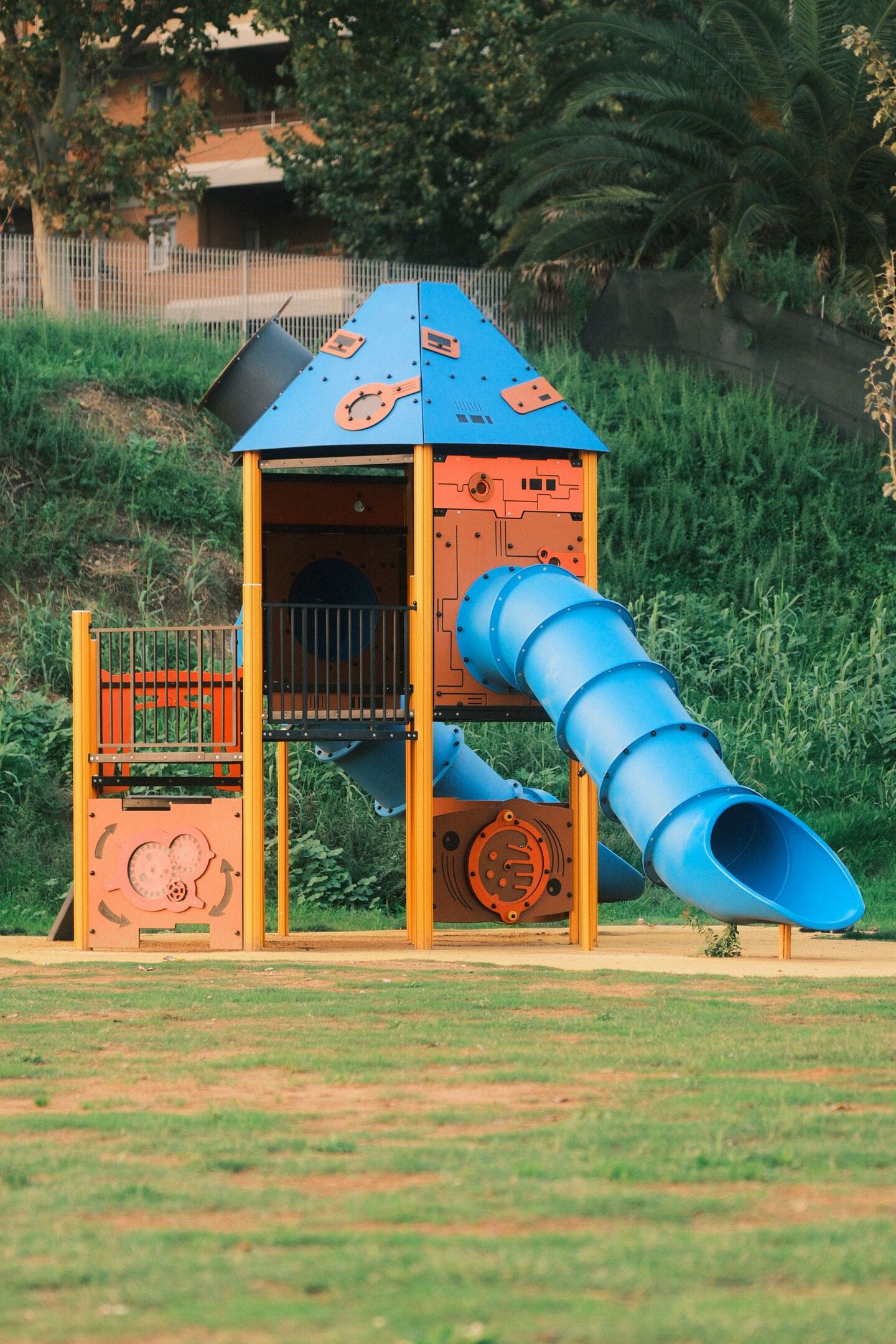 Aire de jeux située dans un parc avec un toboggan métallique bleu