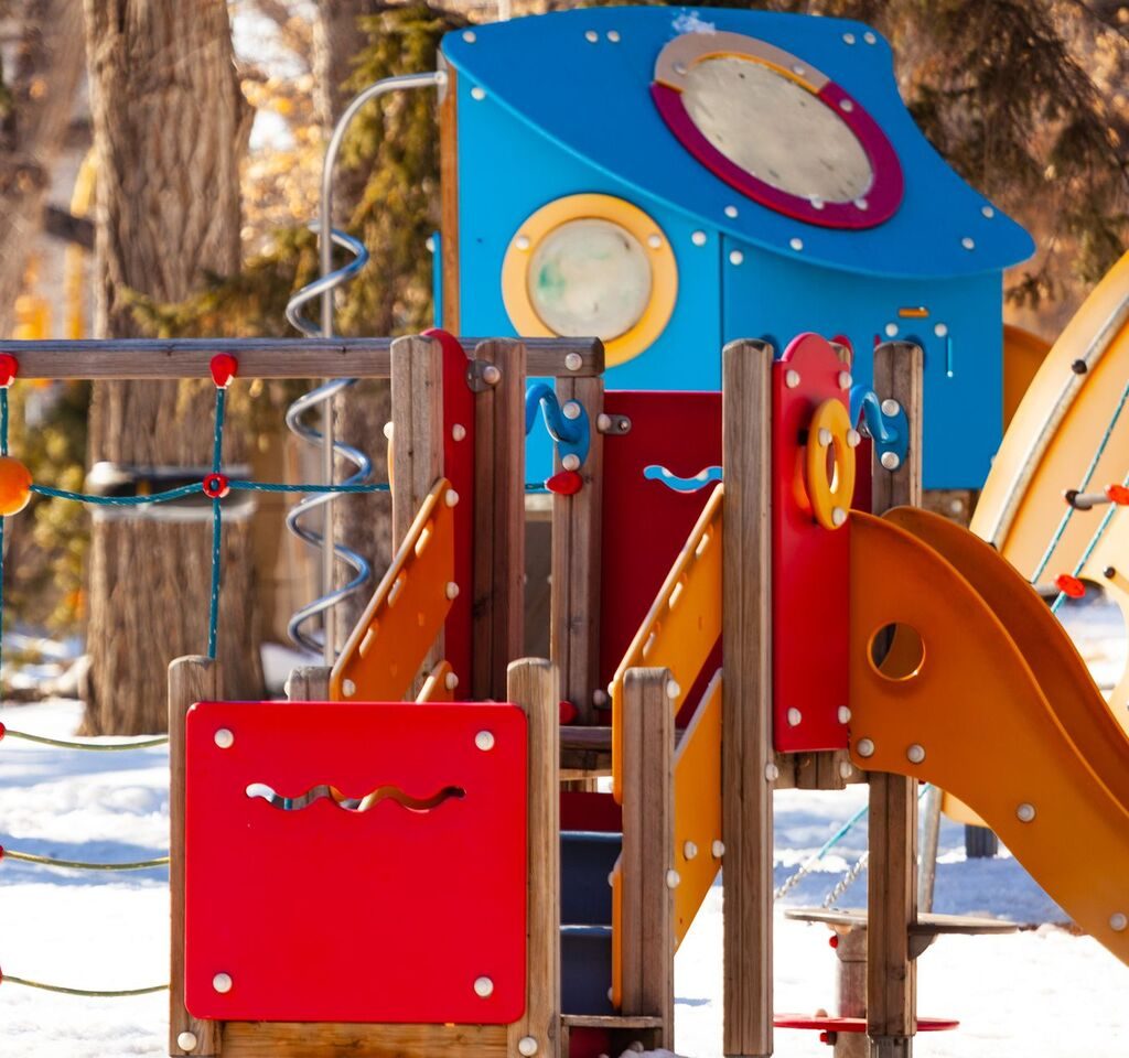 Aire de jeux située dans un parc avec un toboggan métallique orange