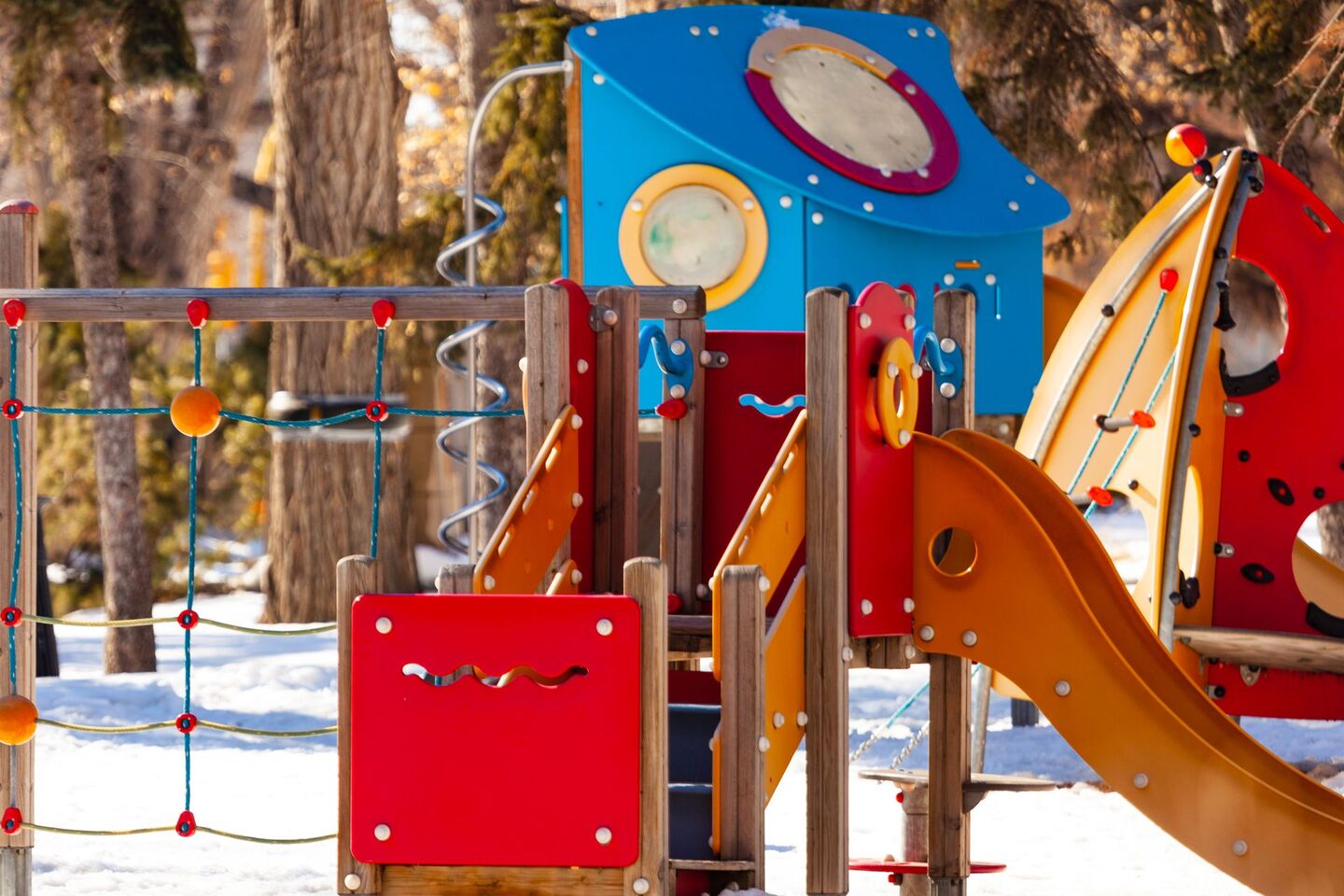 Aire de jeux située dans un parc avec un toboggan métallique orange