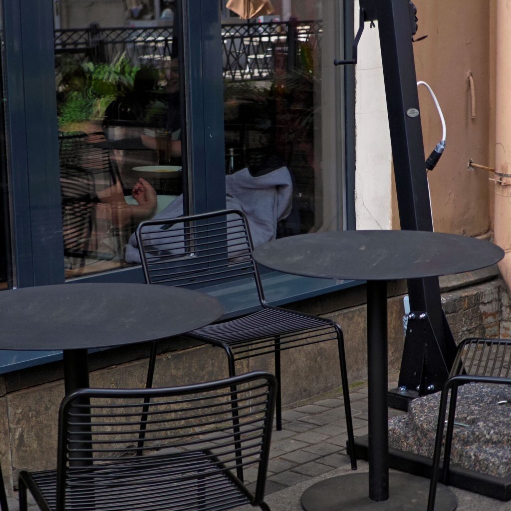 Chaises et tables métalliques noires placées sur une terrasse extérieure d'un restaurant