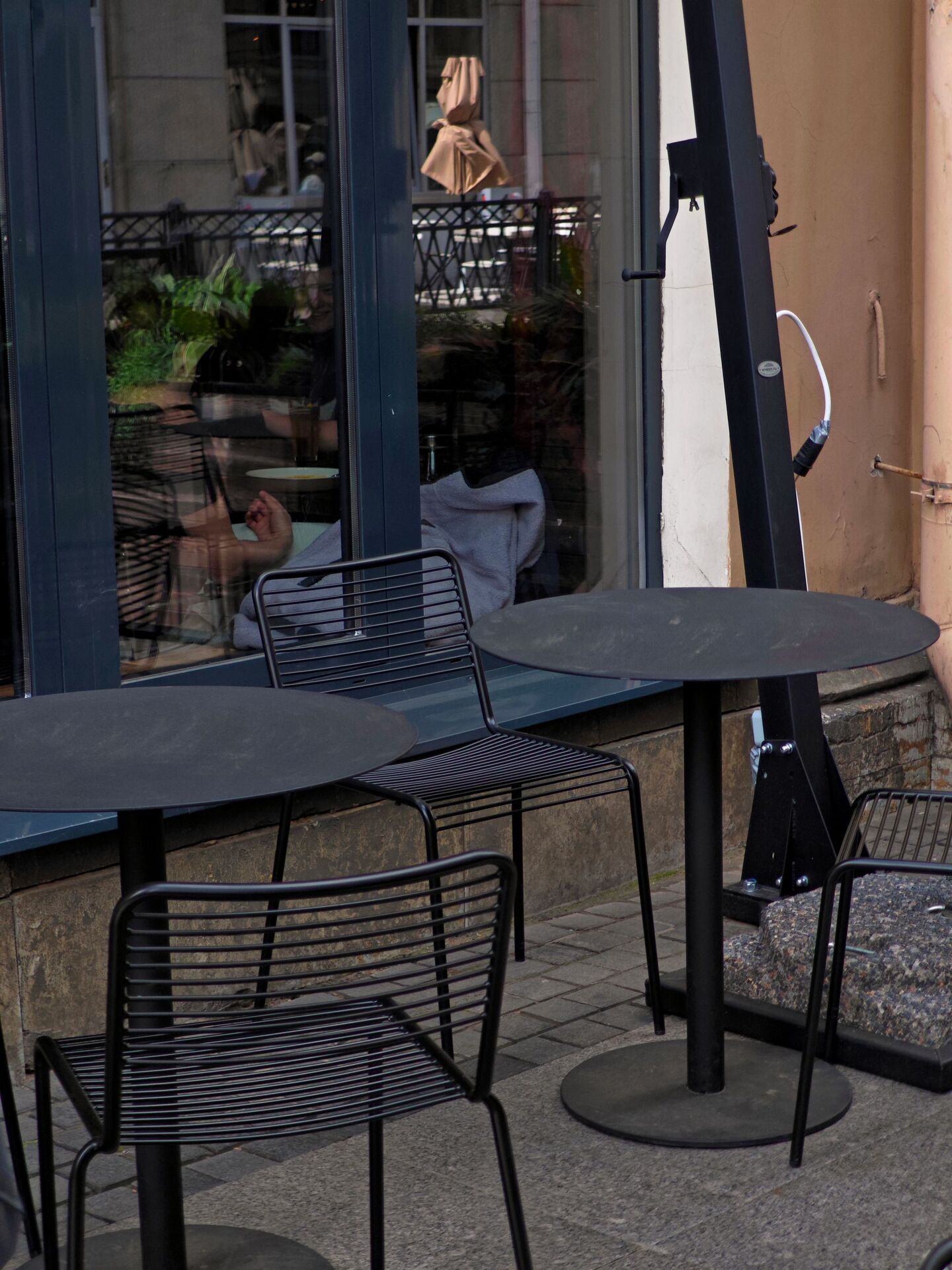 Chaises et tables métalliques noires placées sur une terrasse extérieure d'un restaurant