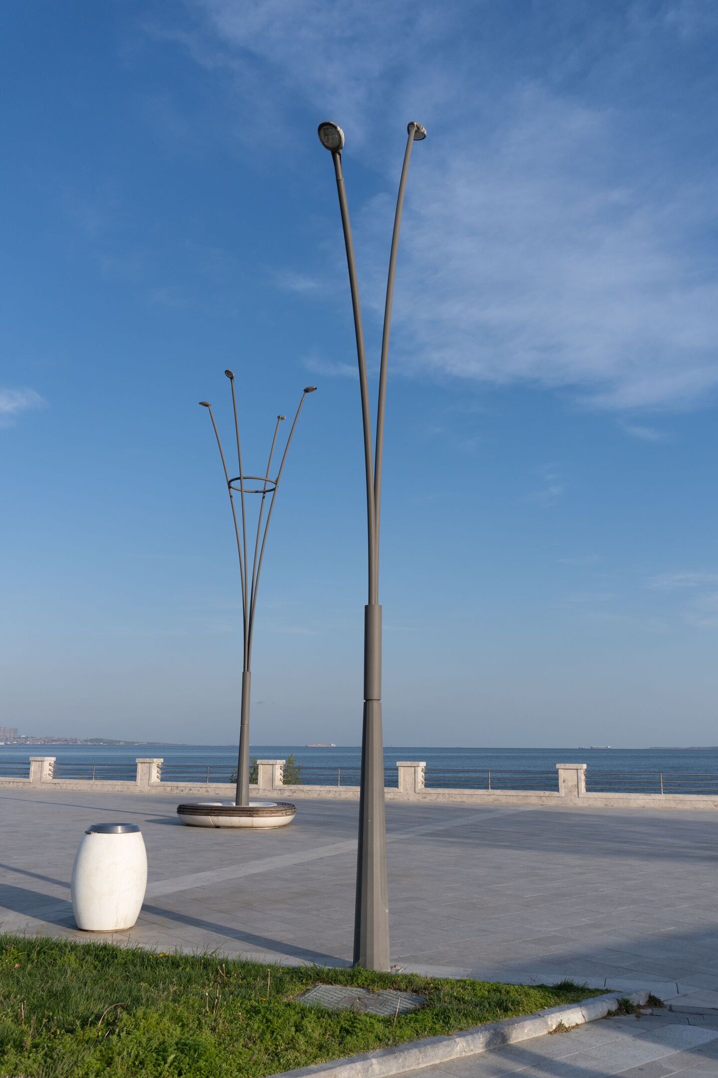 Lampadaires métalliques gris installés sur une rue piétonne au bord de la mer