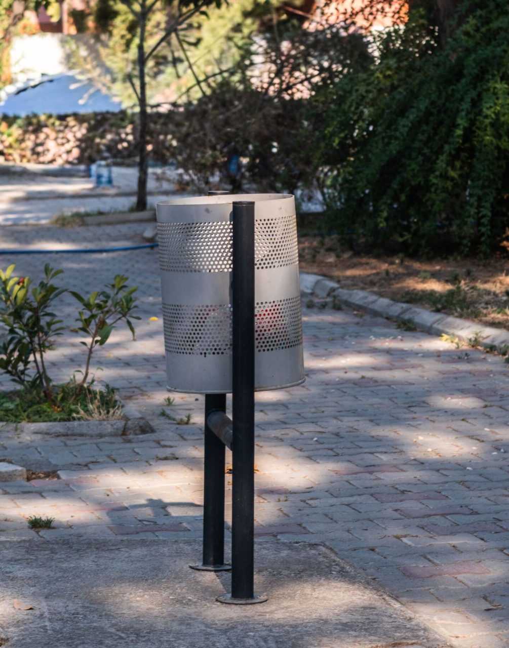 Poubelle métallique grise installée dans un parc