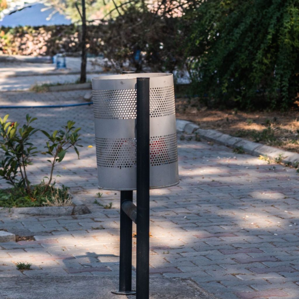 Poubelle métallique grise installée dans un parc