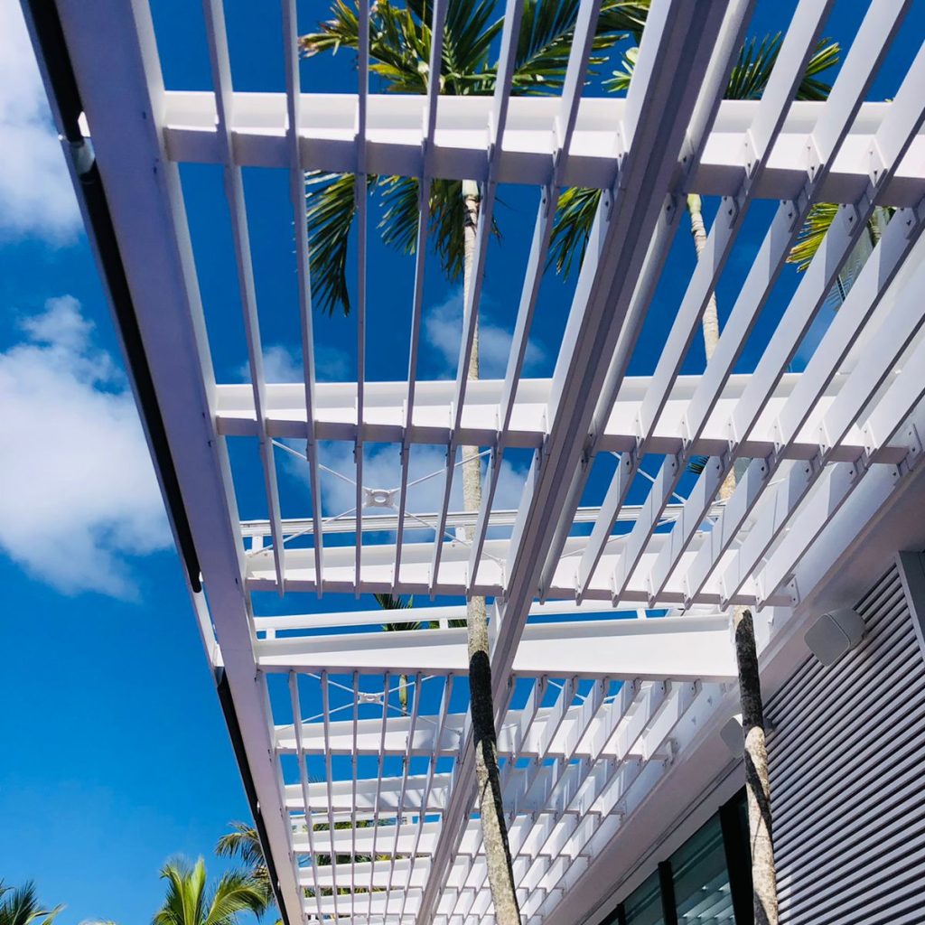Pergola métallique blanche située au-dessus d'une terrasse extérieure