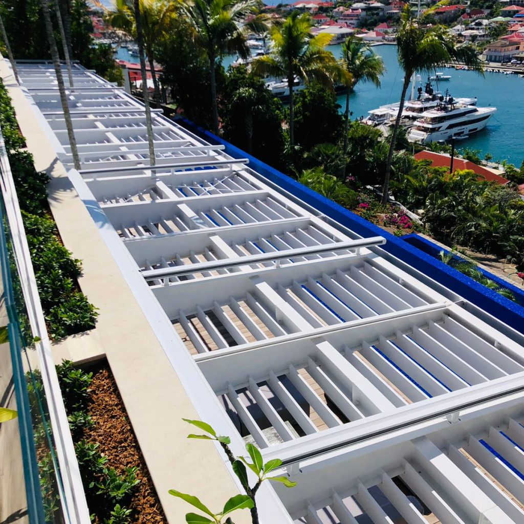 Pergola métallique blanche située au-dessus d'une terrasse extérieure avec une vue sur la mer