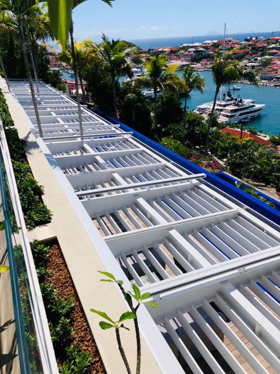 Pergola métallique blanche située au-dessus d'une terrasse extérieure avec une vue sur la mer