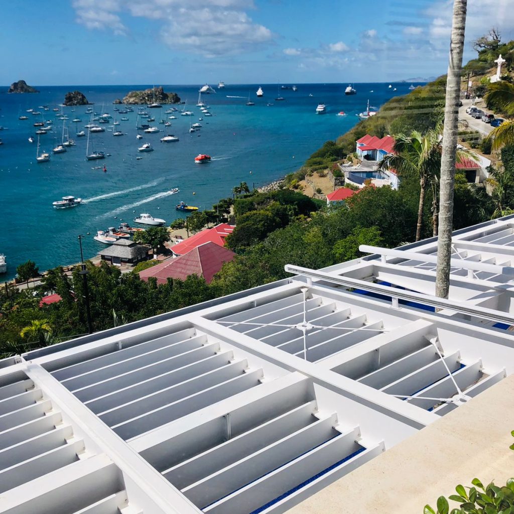 Pergola métallique blanche située au-dessus d'une terrasse extérieure avec une vue sur la mer