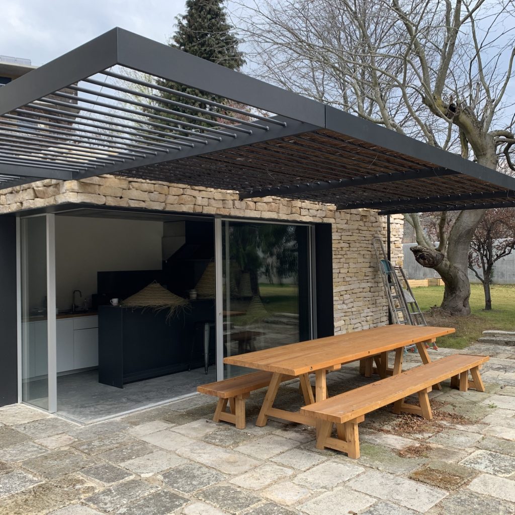 Pergola métallique noire située au-dessus d'une terrasse extérieure