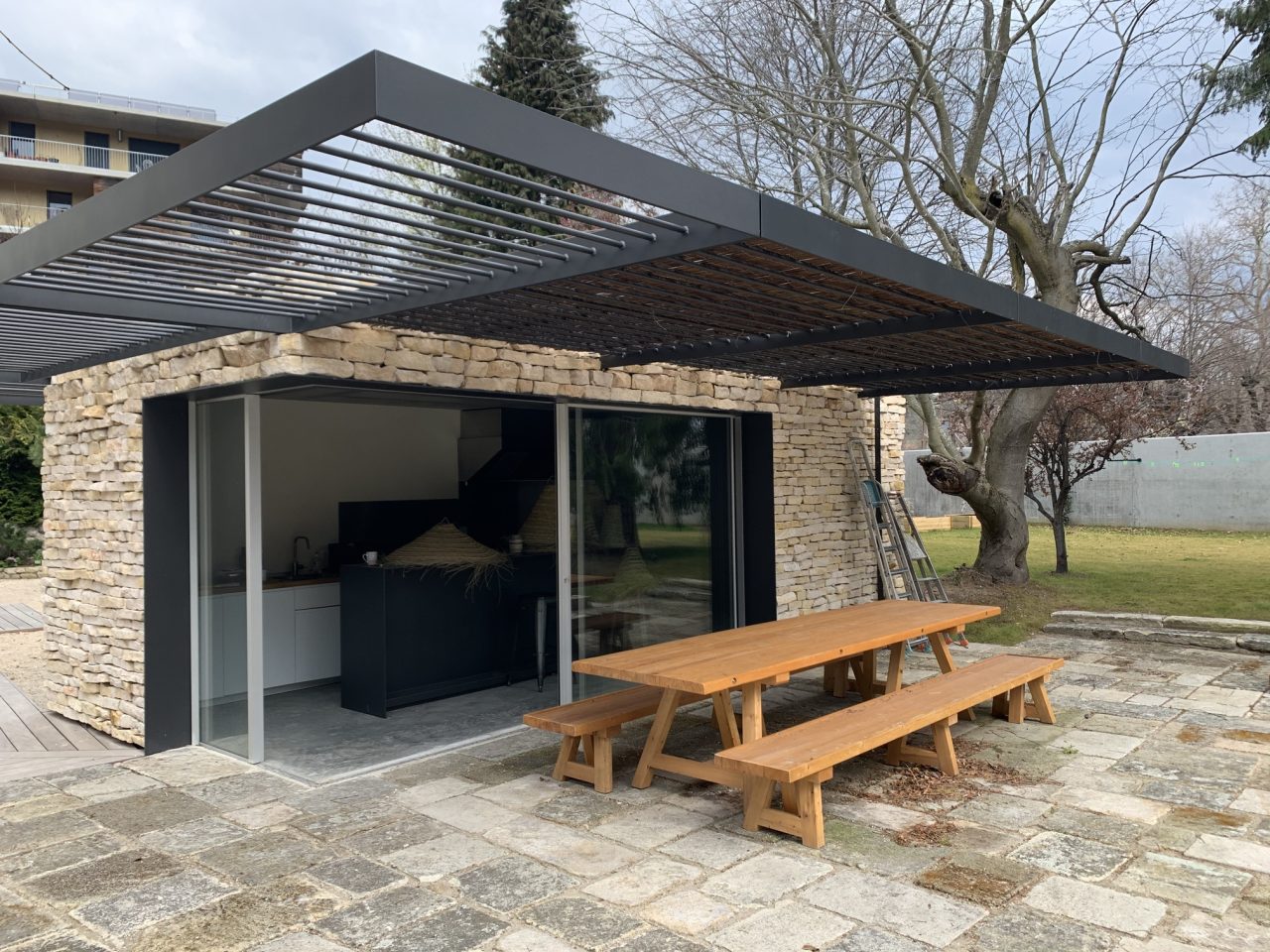 Pergola métallique noire située au-dessus d'une terrasse extérieure