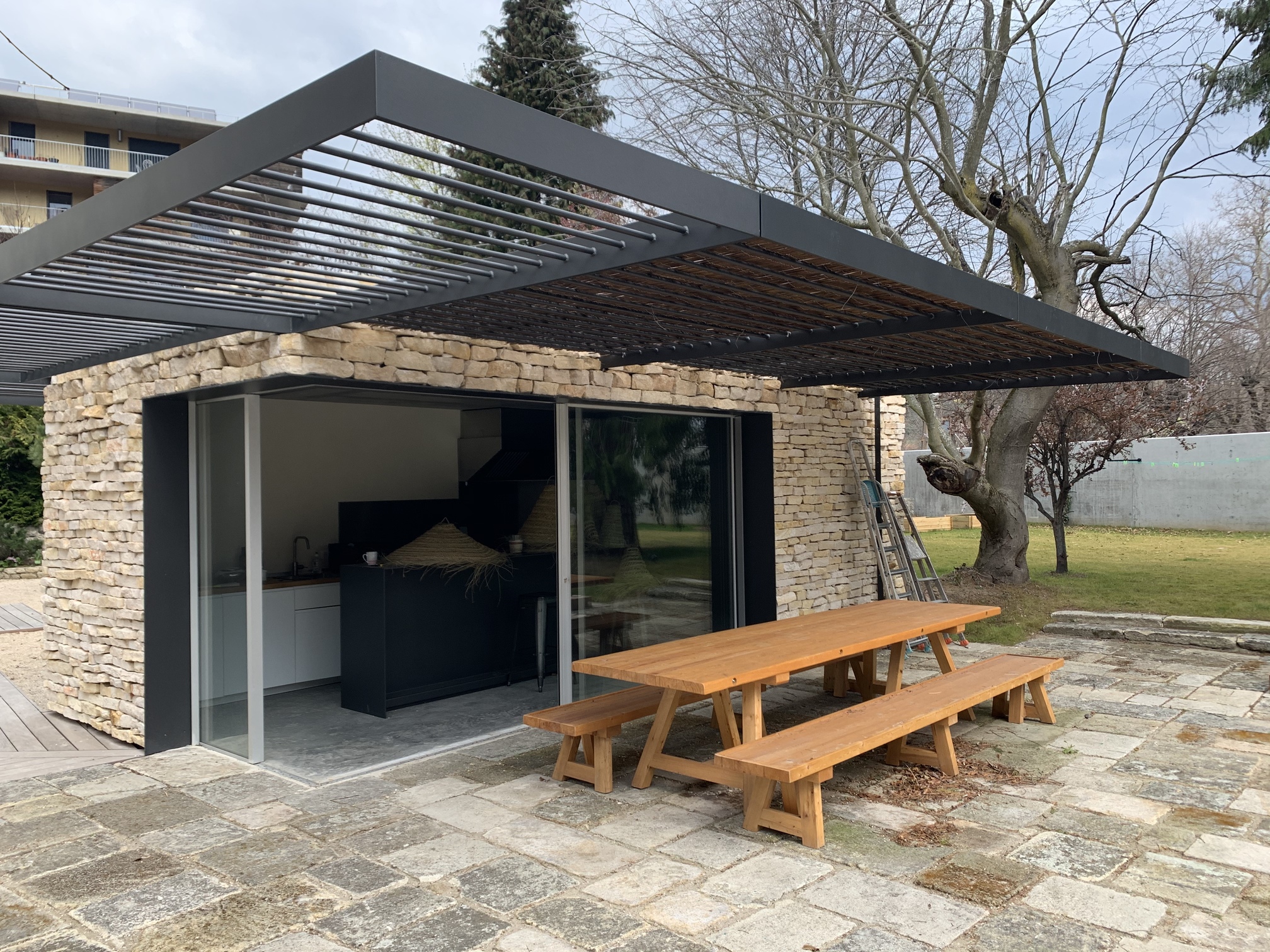 Pergola métallique noire située au-dessus d'une terrasse extérieure