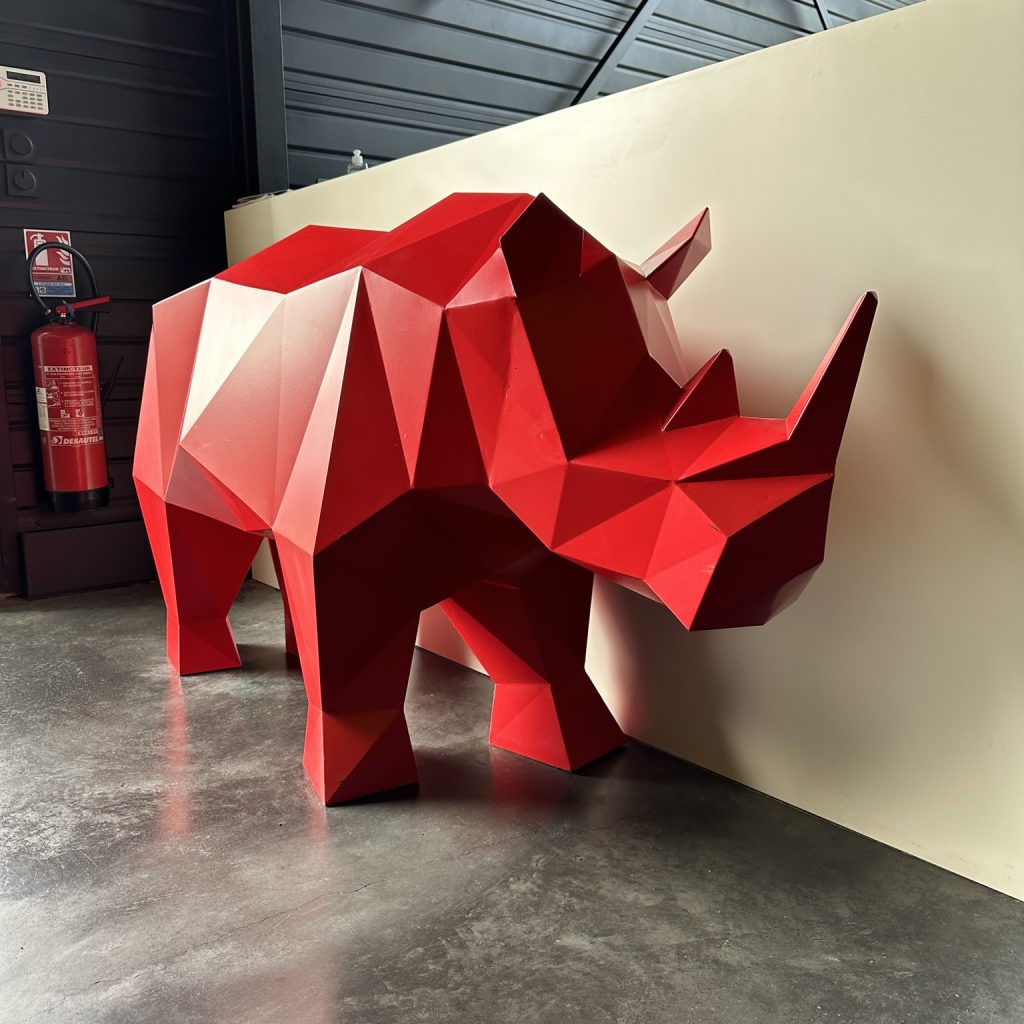 Sculpture métallique rouge représentant un rhinocéros