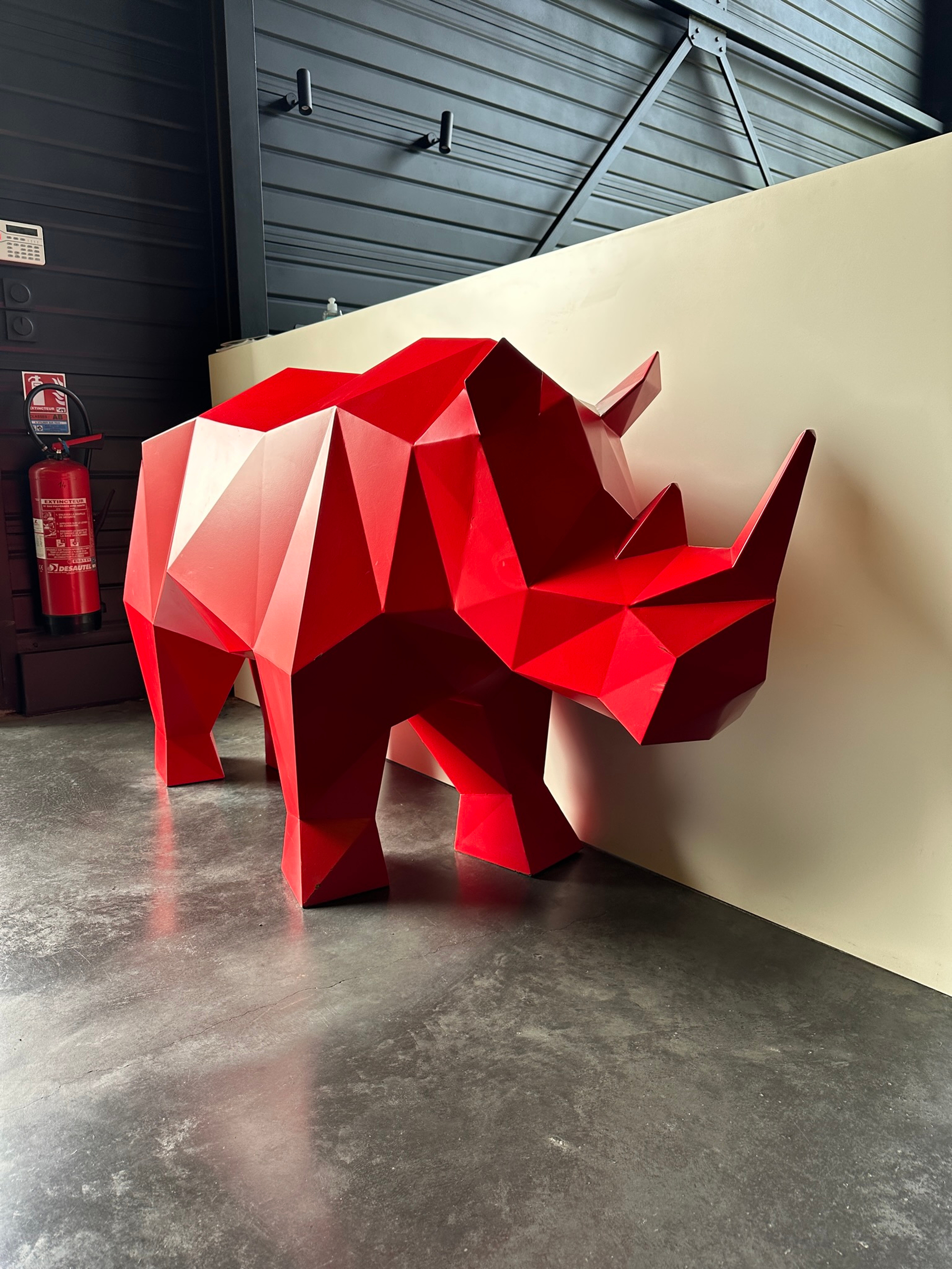Sculpture métallique rouge représentant un rhinocéros